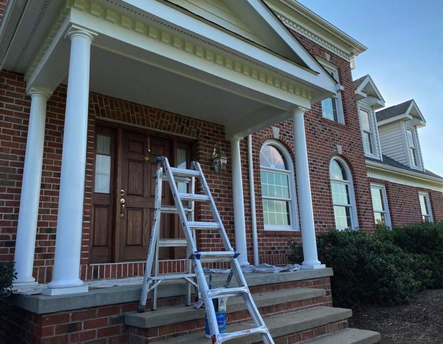 A brick house with a freshly painted white portico, columns and trim