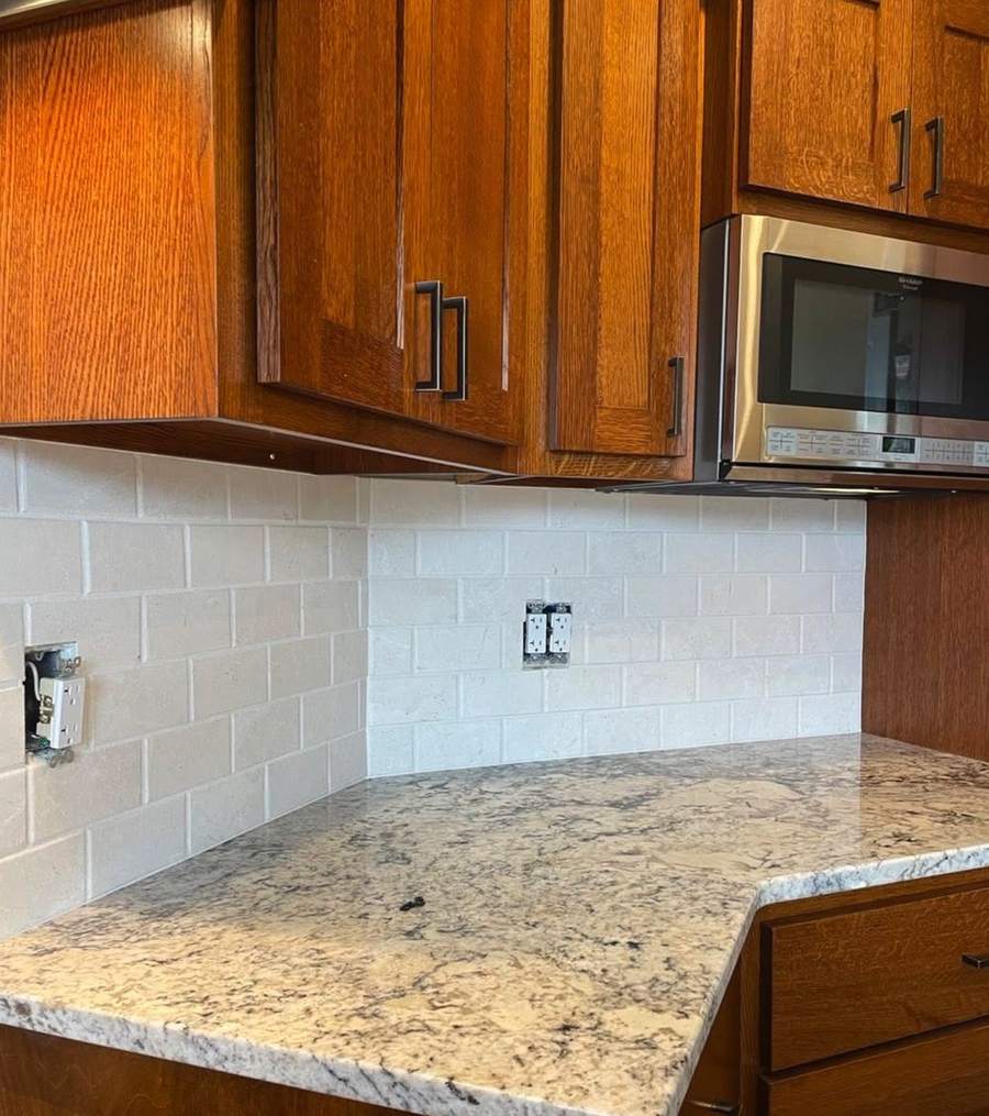 A corner of a kitchen with oak cabinets and new tile