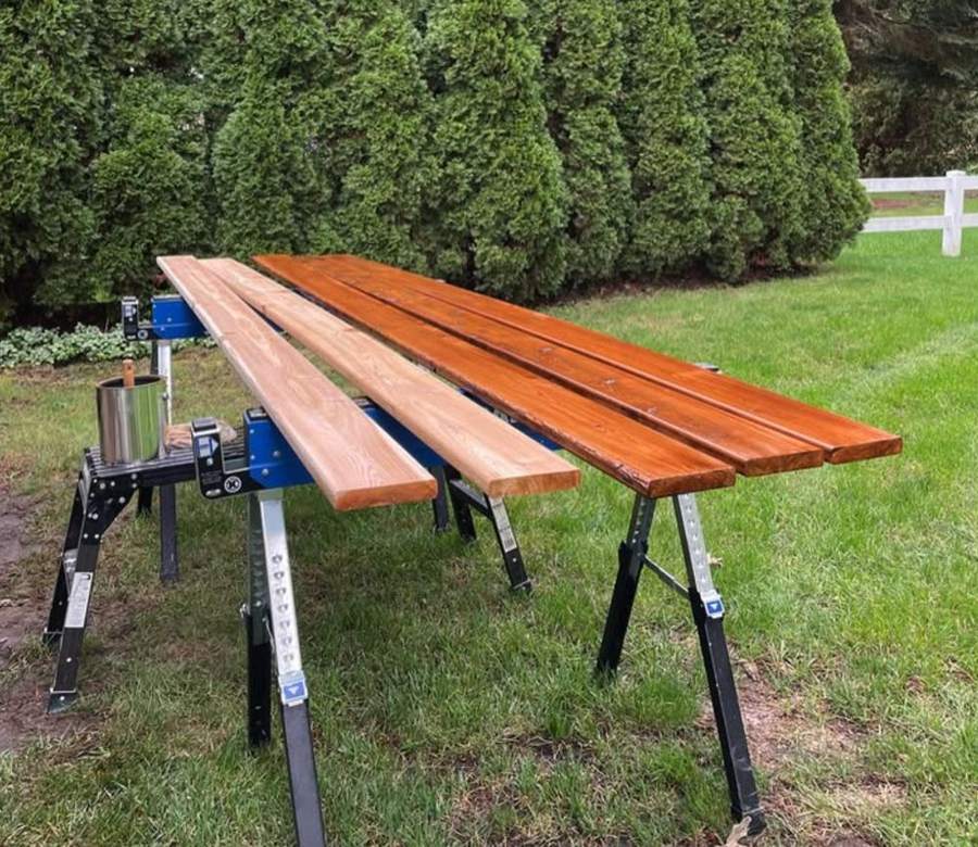 Deck boards on sawhorses, some stained and some bare