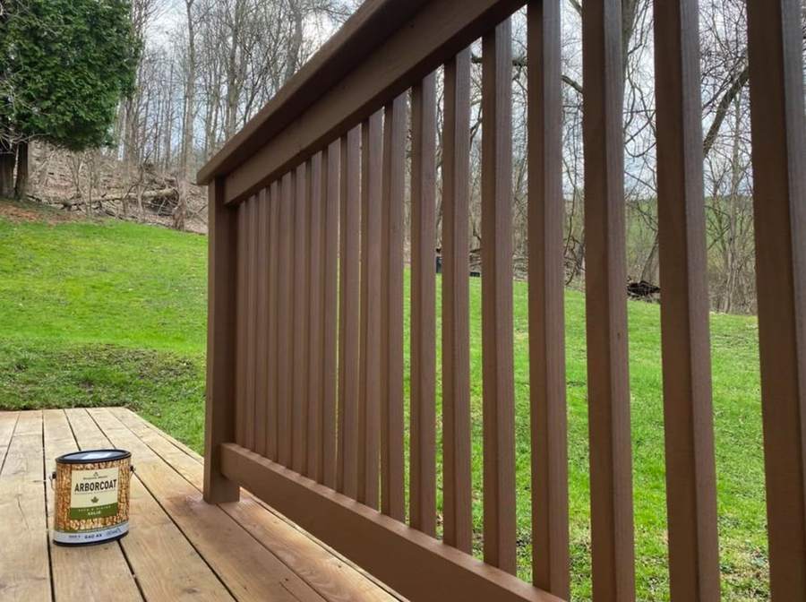 A deck railing finished in solid brown stain