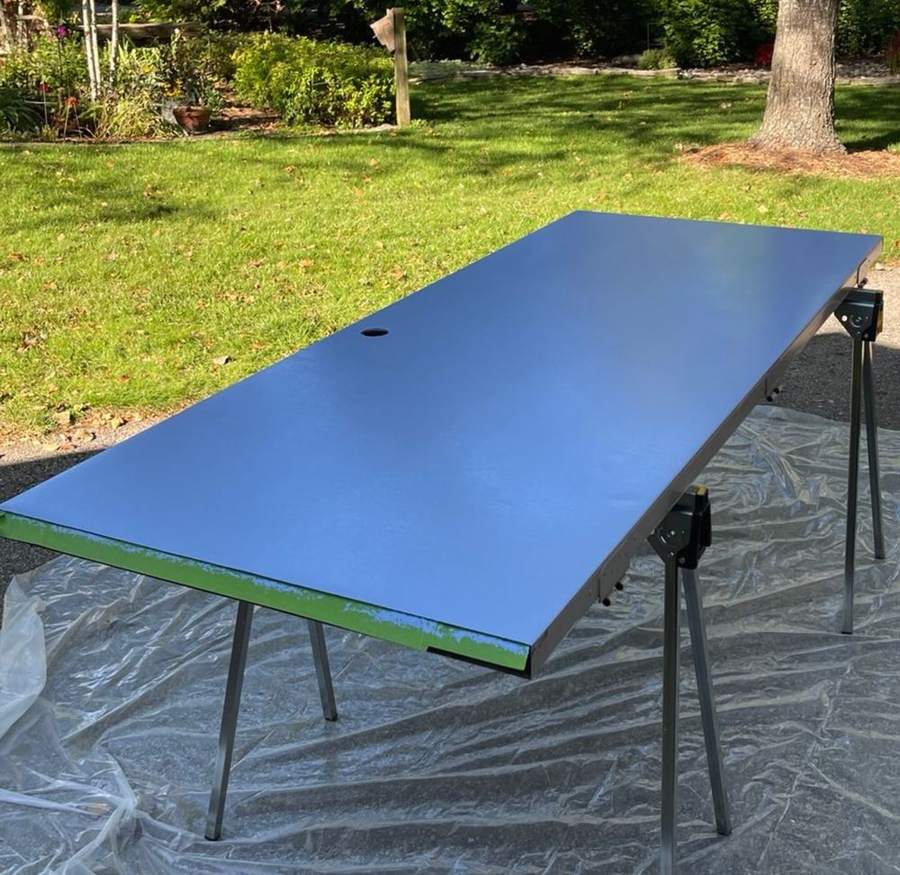 A door laid flat on sawhorses with a fresh coat of blue paint