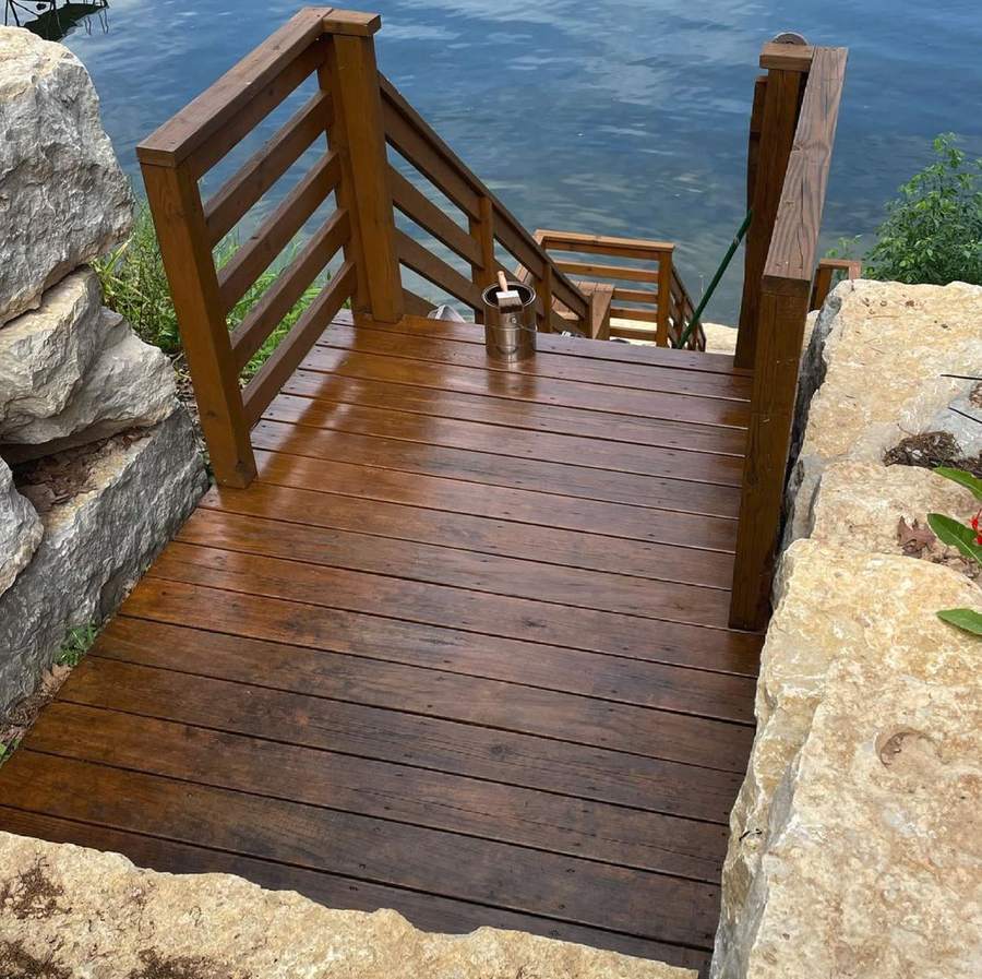 A freshly stained wood landing and stairs leading down to a lake