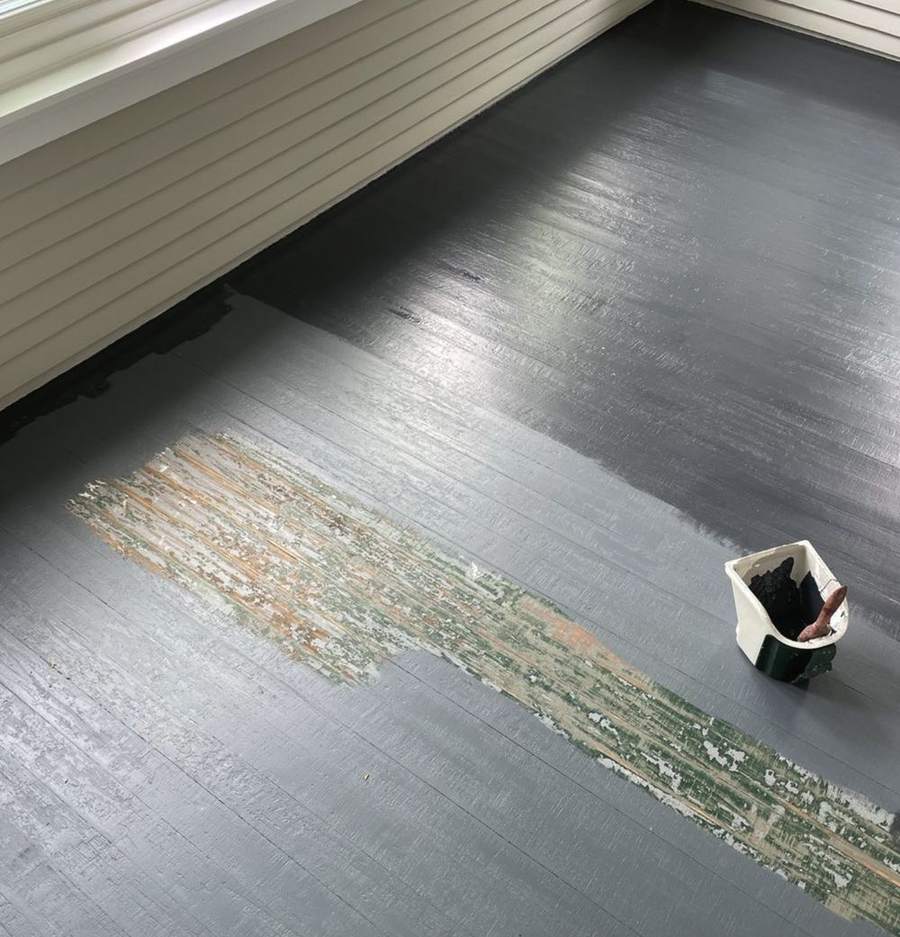 A porch floor with a fresh coat of gray paint going over a worn area