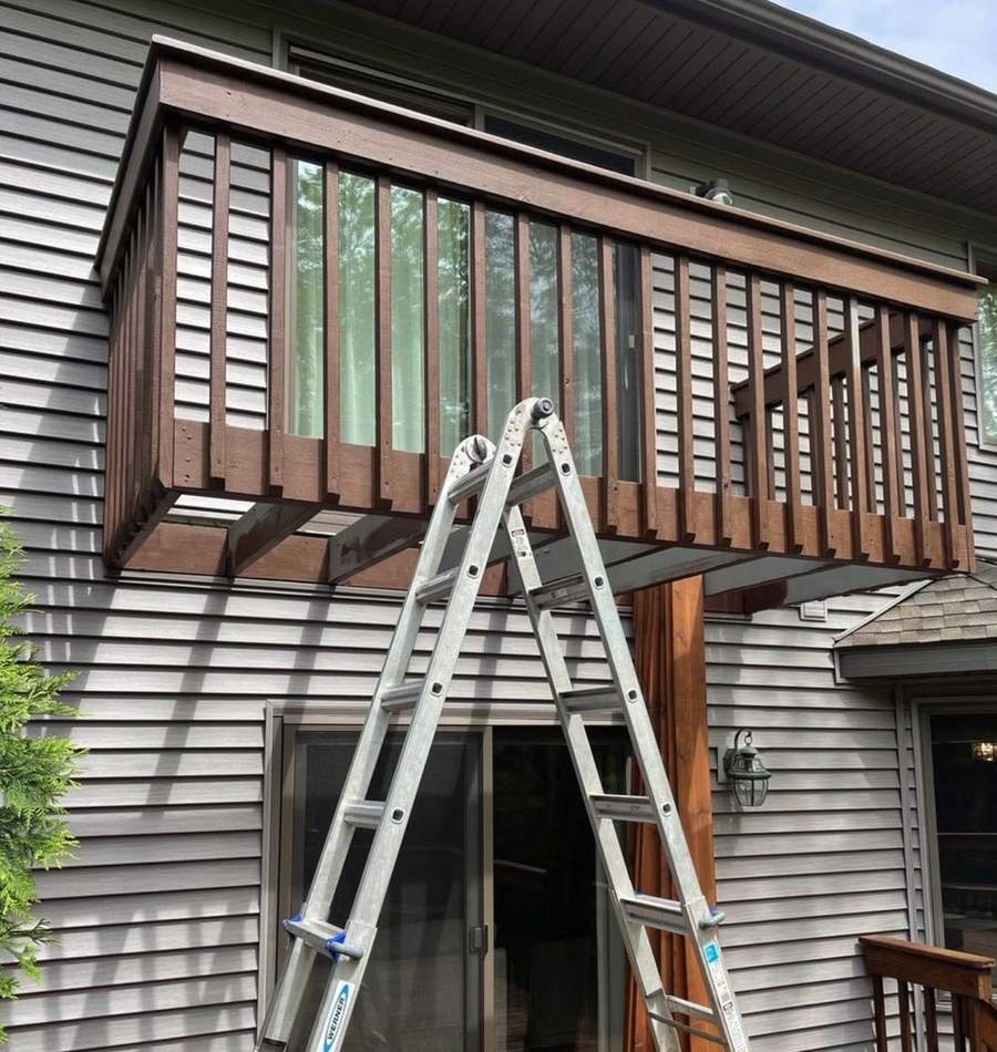 A second-floor wood balcony with stained railings