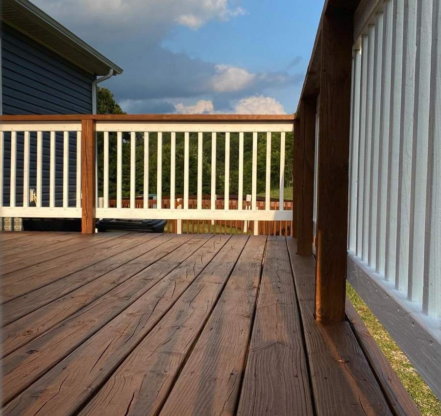 A stained deck with white balusters and stained posts