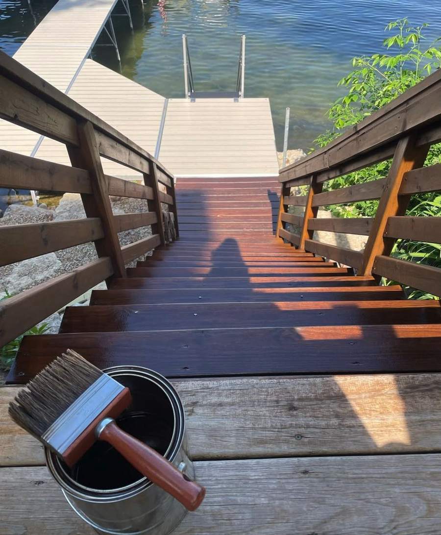 Stained stairs leading down to a dock, with a brush and can in the foreground