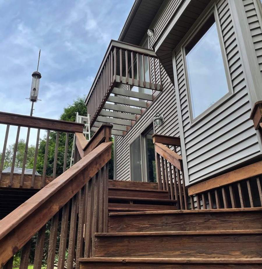 Stained wood deck stairs and railings on the back of a house