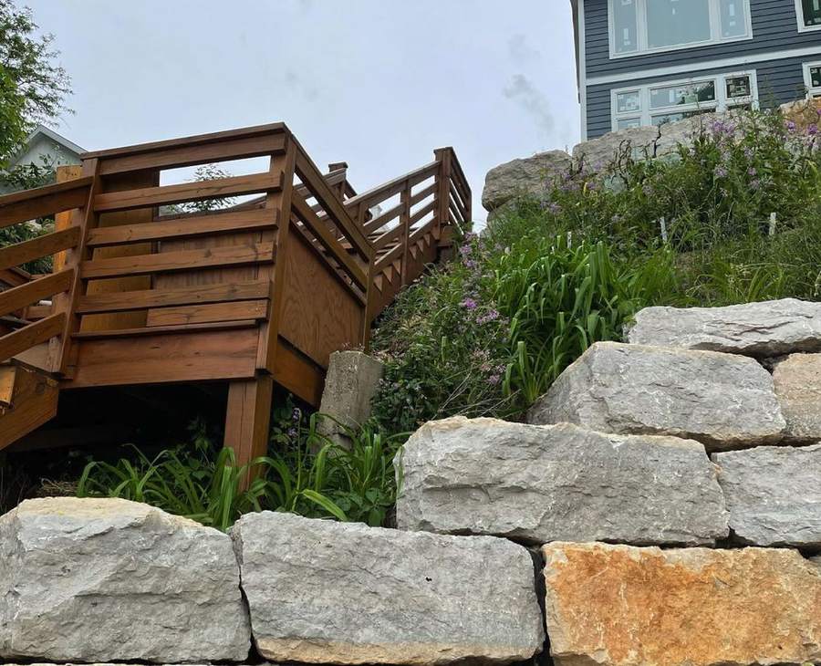 Stained wood stairs seen from below, beside limestone boulders