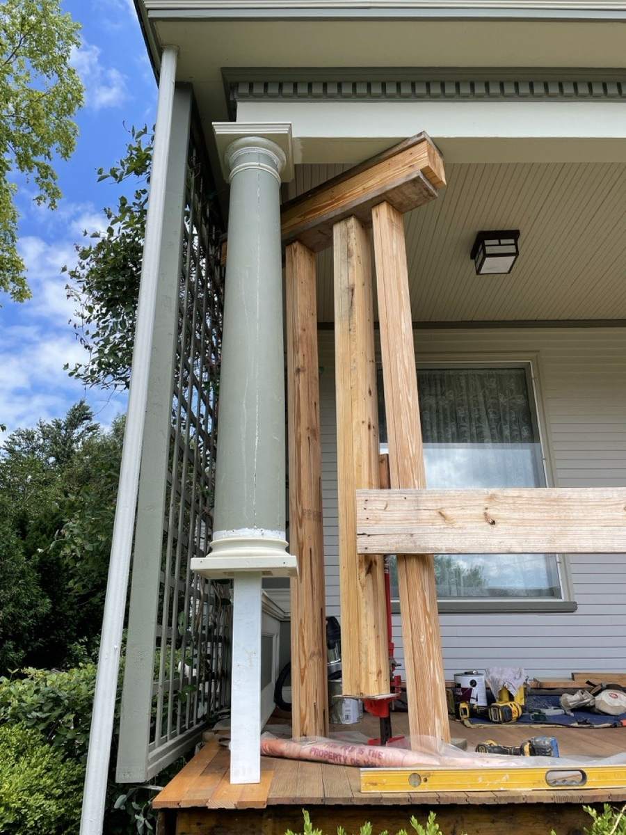 Temporary wood posts holding up the porch roof beside a column