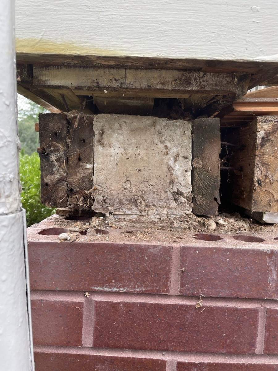 The top of a brick pier with old wood exposed