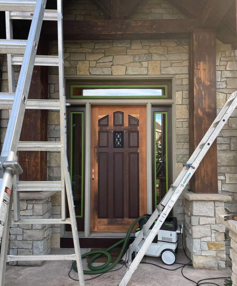 A wood front door with its old finish partly stripped, set in a stone entry