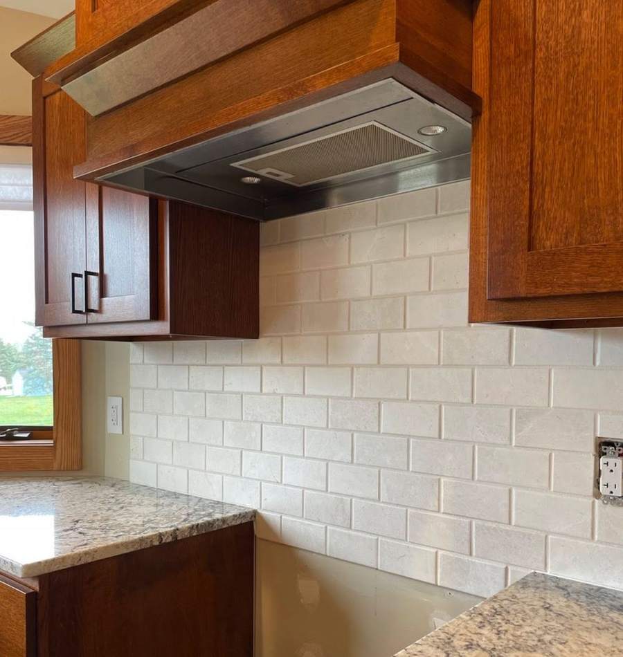 A wood range hood over a new tile backsplash